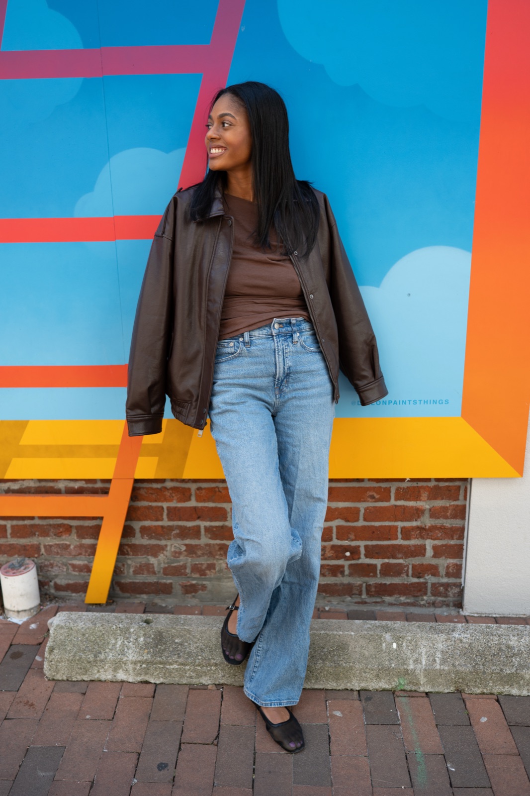 Rukiya Ross smiling in front of a colorful mural
